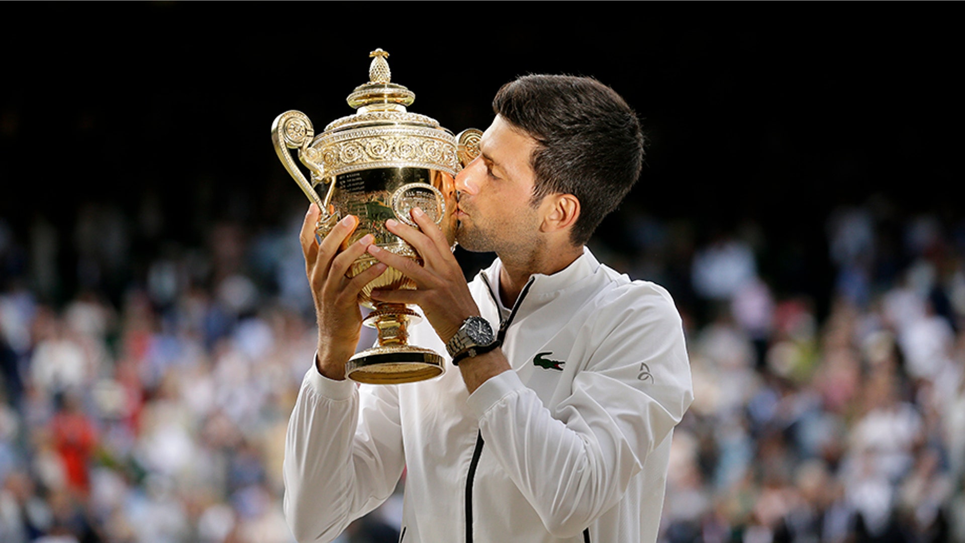 Serbia's Novak Djokovic kisses the trophy after defeating Roger Federer in the men's singles final at the Wimbledon Tennis Championships in London, July 14, 2019. 