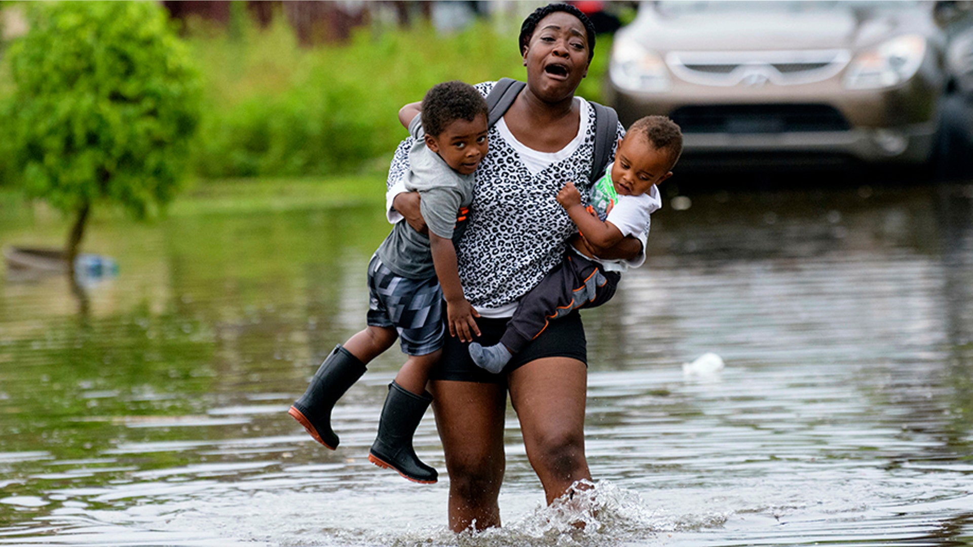 Terrian Jones carries Drew and Chance Furlough during flooding from a storm in the Gulf Mexico in New Orleans, July 10, 2019.
