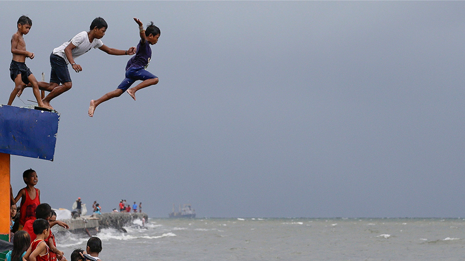 Boys jump into the water after a strong downpour at Manila's Bay, Philippines, July 17, 2019. 