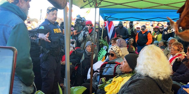 Officers from the Hawaii Department of Land and Natural Resources prepare to arrest protesters, many of them elderly, who are blocking a road to prevent construction of a giant telescope on a mountain that some Native Hawaiians consider sacred, on Mauna Kea on the Big Island of Hawaii, July 17, 2019. (Cindy Ellen Russell/Honolulu Star-Advertiser via AP)
