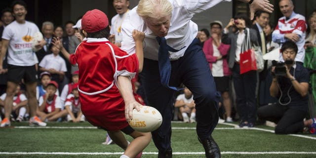 In this Oct. 15, 2015 file photo, Boris Johnson takes part in a Street Rugby tournament in a Tokyo street, wiping out a Japanese school boy in the process