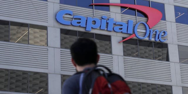 In this July 16, 2019, photo, a man walks across the street from a Capital One location in San Francisco. Capital One says a hacker got access to the personal information of over 100 million individuals applying for credit.