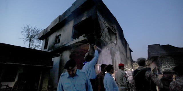 Pakistan army troops and police officers gather at the site of a plane crash in Rawalpindi, Pakistan, Tuesday, July 30, 2019. A small Pakistani military plane crashed into a residential area near the garrison city of Rawalpindi before dawn, killing some people, officials said.