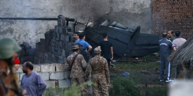 Pakistan army officials examine the site of a plane crash in Rawalpindi, Pakistan, Tuesday, July 30, 2019. A small Pakistani military plane crashed into a residential area near the garrison city of Rawalpindi before dawn, killing some people, officials said.