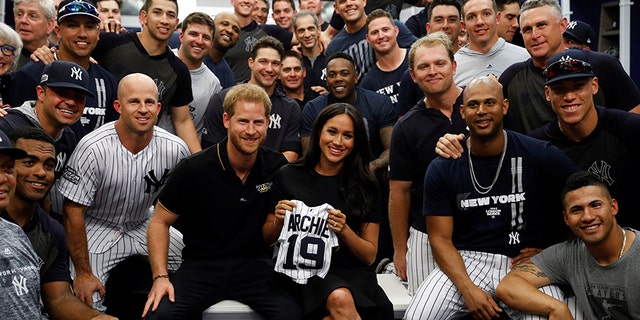 Britain's Prince Harry and Meghan, Duchess of Sussex pose for a picture with players of the New York Yankees before a match against the Boston Red Sox in London, on June 29, 2019. 