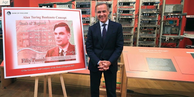 The governor of the Bank of England, Mark Carney, poses for a photo with the artwork for the concept of the new 50-pound notes, after announcing this month that the notes would honor Alan Turing. (AP)