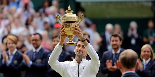 Serbian Novak Djokovic raises his trophy after defeating Switzerland's Roger Federer in the final match of the men's singles at the Wimbledon Tennis Championships in London on Sunday 14 July 2019. (AP Photo / Ben Curtis)