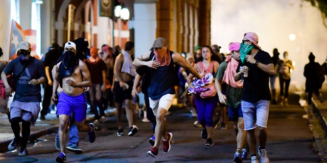 Demonstrators affected by tear gas thrown by the police run during clashes in San Juan on Monday.