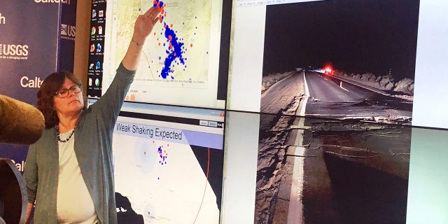 Lucy Jones, a seismologist at the California Institute of Technology and a former science adviser at the U.S. Geological Survey, points to a display of earthquakes during a news conference at CalTech in Pasadena, Calif., Friday evening, July 5, 2019. At right is a USGS photo of broken pavement on state route 178 near Trona, Calif. (Associated Press)