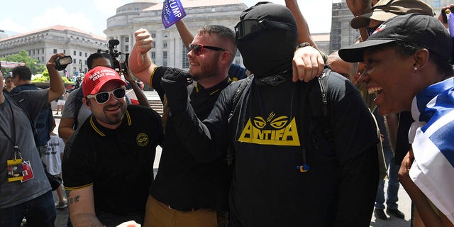 People attending a "Demand Free Speech" rally in Washington, Saturday, July 6, 2019, gather around an opposing protester for a photo. The rally was organized to protest against the perceived censorship of conservative views. (Associated Press)