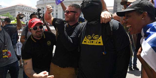 People attending a "Demand Free Speech" rally in Washington, Saturday, July 6, 2019, gather around an opposing protester for a photo. The rally was organized to protest against the perceived censorship of conservative views. (Associated Press)