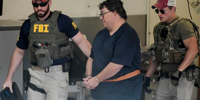 FBI agents escort businessman Fernando Scherrer-Caillet. (AP Photo/Carlos Giusti)