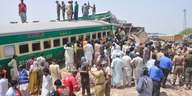 Pakistani officials and volunteers work at a train crash site in Rahim Yar Khan, Pakistan, Thursday, July 11, 2019. A passenger train rammed into a freight train in southern Pakistan on Thursday, killing many people and injuring others, an official said. (AP Photo/Waleed Saddique)