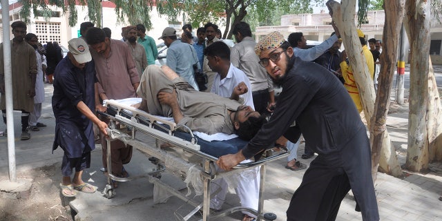 People rush an injured passenger to a hospital in Rahim Yar Khan, Pakistan, Thursday, July 11, 2019. A passenger train rammed into a freight train in southern Pakistan on Thursday, killing many people and injuring others, an official said. (AP Photo/Waleed Saddique)