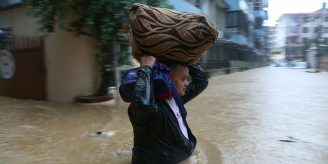 A Nepalese man wades with his belonging through a flooded street in Kathmandu, Nepal on Friday. (AP Photo/Niranjan Shrestha)