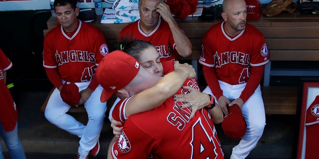 Debbie Hetman, center left, mother of the late pitcher Tyler Skaggs, hugs Angels outfielder Andrew Heaney before the first home game after Skagg's death. (AP Photo/Marcio Jose Sanchez)