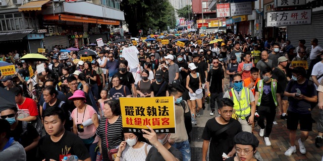 Protesters hold up words that read: "Strict enforcing of law against smugglers of grey goods" in Hong Kong Saturday, July 13, 2019. Several thousand people are marching in Hong Kong against traders from mainland China in what is fast becoming a summer of unrest in the semi-autonomous Chinese territory. (AP Photo/Kin Cheung)