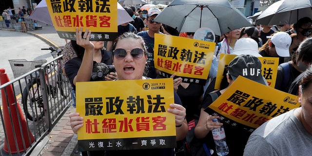 Protesters hold up words that read: "Strict enforcing of law against smugglers of grey goods" in Hong Kong Saturday, July 13, 2019. Several thousand people are marching in Hong Kong against traders from mainland China in what is fast becoming a summer of unrest in the semi-autonomous Chinese territory. (AP Photo/Kin Cheung)