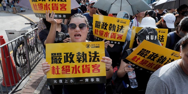 Protesters hold up words that read: "Strict enforcing of law against smugglers of grey goods" in Hong Kong Saturday, July 13, 2019. Several thousand people are marching in Hong Kong against traders from mainland China in what is fast becoming a summer of unrest in the semi-autonomous Chinese territory. (AP Photo/Kin Cheung)