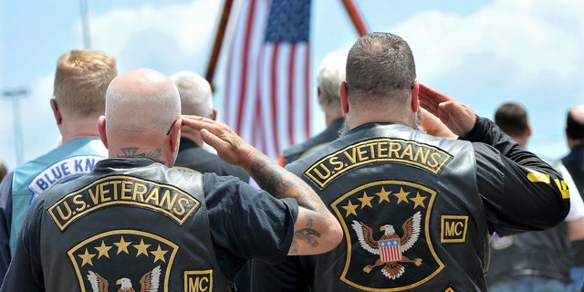 Members of the biker club of American veterans greet the flag during the reading of the national anthem. (Mark Stockwell / The Sun Chronicle via AP)