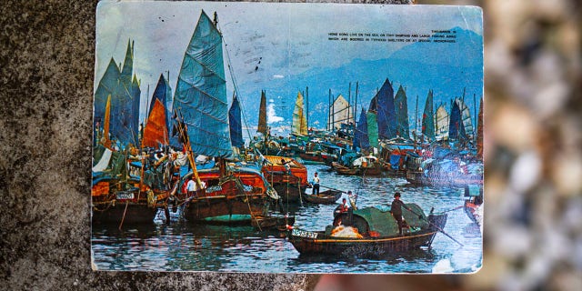 Kim Draper received a postcard, which depicts a scene of fishing boats in Hong Kong, at her home in Springfield on July 8, 2019 that was postmarked and sent from Hong Kong exactly 26 years ago on July 8, 1993 to a previous family that lived at her address. (Justin L. Fowler/The State Journal-Register via AP)