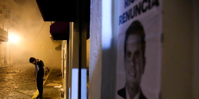 Protester stands near a poster calling for the resignation of Governor Ricardo Rosselo, in San Juan, Puerto Rico, on Monday. (AP Photo / Carlos Giusti)
