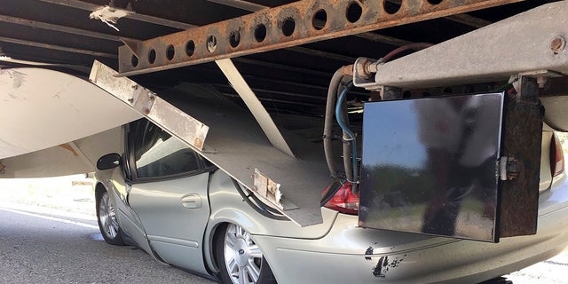 In this Tuesday, July 16, 2019 photo photo released by the Uxbridge Fire Department on its Facebook page, a car sits wedged under a tractor-trailer on Route 146 in Uxbridge, Mass. The motorist<br>
climbed out of the driver's side door of the crushed car and wasn't seriously hurt. (Uxbridge Fire Department via AP)