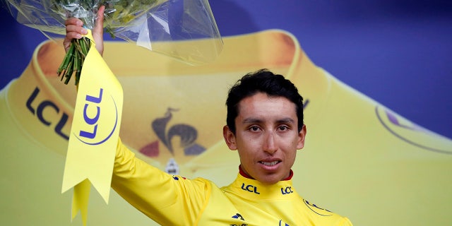 New overall leader Colombia's Egan Arley Bernal Gomez wearing the yellow jersey celebrates on the podium after the nineteenth stage of the Tour de France cycling race with start in Saint Jean De Maurienne, France, Friday, July 26, 2019. Tour de France organizers stopped Stage 19 of the race because of a hail storm as Julien Alaphilippe lost his yellow jersey to Egan Bernal. (AP Photo/Christophe Ena)