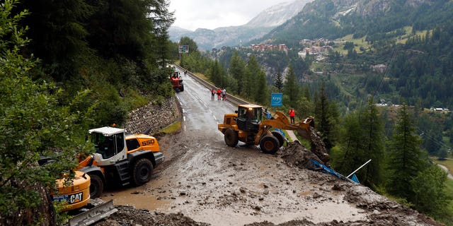 Worker use diggers to clean the road of the nineteenth stage of the Tour de France cycling race over 78,60 miles with start in Saint Jean De Maurienne and finish in Tignes, France.
