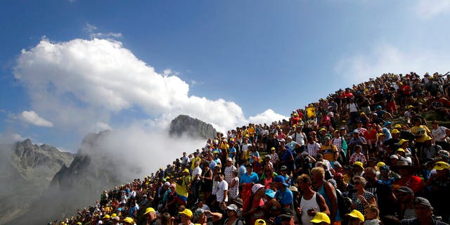 Spectators stand on the Tourmalet pass next to the finish line of the fourteenth stage of the Tour de France cycling race over 73 miles with a start in Tarbes and finish at the Tourmalet pass.