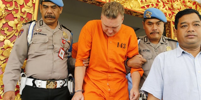 Police officers escort Australian national David van Iersel, center, to a press conference at the regional police headquarters in Denpasar, Bali, Indonesia Tuesday, July 23, 2019. Indonesian police say two Australian men have been arrested with cocaine on Bali. (AP Photo/Firdia Lisnawati)