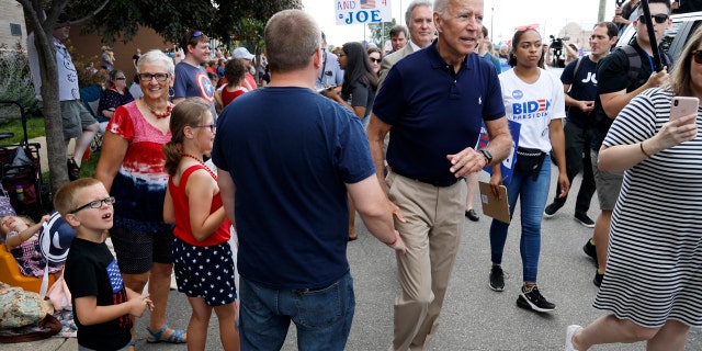 Former Vice President and Democratic presidential candidate Joe Biden greets local residents while walking in the Independence Fourth of July parade on Thursday in Independence, Iowa. (AP Photo/Charlie Neibergall)