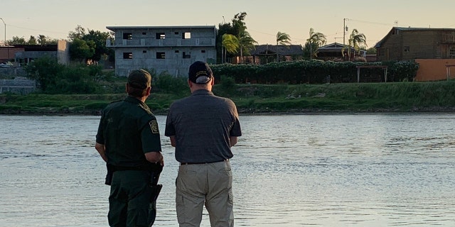 A U.S. Border Patrol official and the U.S. Drug Czar Jim Carroll look across the Rio Grande--the river that separates the U.S. and Mexico.