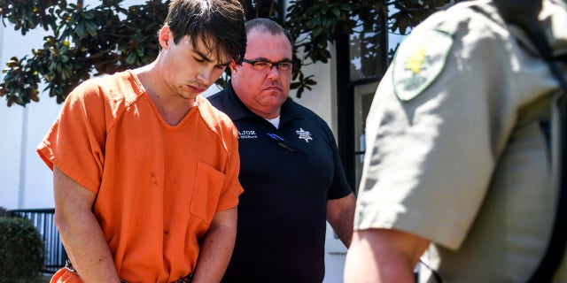 Brandon Theesfeld, left, is led from the Lafayette County Courthouse in Oxford, Miss., Tuesday, July 23, 2019 by Maj. Alan Wilburn.