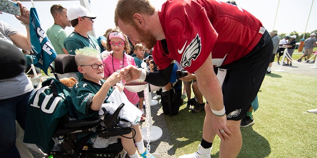 Philadelphia Eagles quarterback Carson Wentz bumps fists with eleven-year-old Giovanni Hamilton who is attending the practice as part of a wish granted by Bianca's Kids at the NFL football team's training camp in Philadelphia, Friday, July 26, 2019. (AP Photo/Matt Rourke)