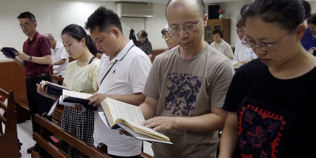 In this Sunday, July 7, 2019, photo, from right; Ren Dejun, Liao Qiang, Peng Ran and Ren Ruiting follow a hymn book during service at a church in Taipei, Taiwan. The Sunday service this week at an unassuming church in Taiwan was especially moving for one man, Liao Qiang. It was the first time he had worshipped publicly since authorities shut down his church in China seven months ago. (AP Photo/Chiang Ying-ying)