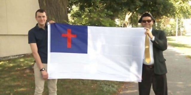 Nathaniel Shurtleff, counselor, and Tom Moor, instructor, for Camp Constitution hold the Christian flag, which was not allowed to fly by the city of Boston in 2017 and 2018. Now the group is suing the city for religious discrimination. 