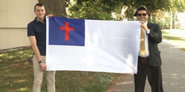 Nathaniel Shurtleff, counselor, and Tom Moor, instructor, for Camp Constitution hold the Christian flag, which was not allowed to fly by the city of Boston in 2017 and 2018. Now the group is suing the city for religious discrimination. 