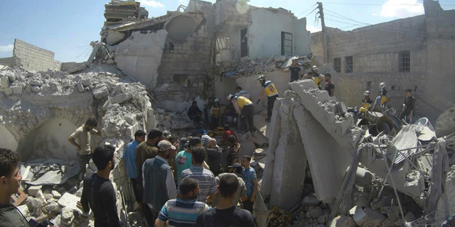 This photo provided by the Syrian Civil Defense White Helmets, which has been authenticated based on its contents and other AP reporting, shows Syrian White Helmet civil defense workers searchING for victims from under the rubble of a destroyed building that hit by a Syrian government airstrike, in the northern town of Ariha, in Idlib Province, Syria, earlier this month. (Syrian Civil Defense White Helmets via AP)