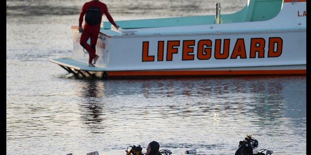 In this April 9, 2015, photo, divers emerge from the water as debris believed to be from a car floats to the surface in Los Angeles' San Pedro harbor district. Los Angeles prosecutors have charged an Egyptian father with murder after he allegedly drove his family off a pier, killing his two autistic sons. (Steve McCrank/The Orange County Register via AP, File)