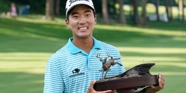 FILE - In this July 15, 2018, file photo, Michael Kim holds the trophy after winning the John Deere Classic golf tournament in Silvis, Ill. Kim had missed six out of seven cuts and changed coaches when he showed up at the John Deere Classic last year. He broke the tournament record at 27-under 257 and won by eight shots, matching Dustin Johnson and Francesco Molinari for the largest victory margin of the season. And then it was as if the week never happened. (AP Photo/Charlie Neibergall, File)