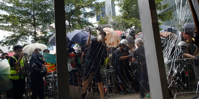 A protester tries to break the glass to get into the Legislative Council in Hong Kong Monday, July 1, 2019.