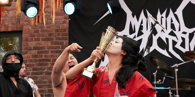 The Japanese team Giga Body Metal reacts with the trophy after being crowned Heavy Metal Knitting world champions with a show featuring crazy sumo wrestlers and team-leader Manabu Kaneko dressed in a traditional Japanese kimono knitting. (AP Photo/David Keyton)