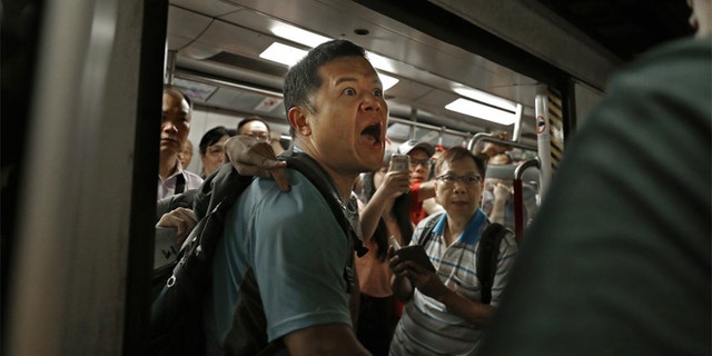 A passenger reacts after protesters blocked the train doors stopping the trains leaving at a subway platform in Hong Kong Wednesday morning. Subway train service was disrupted during morning rush hour after dozens of protesters staged what they called a disobedience movement to protest over a Sunday mob attack at a subway station. (AP Photo/Vincent Yu)