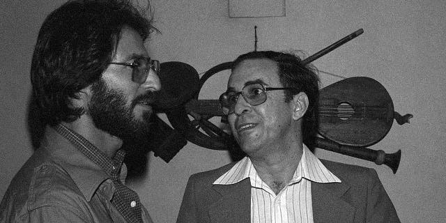 FILE - In this July 1978 file photo, Brazilian Joao Gilberto, right, chats backstage with a fan at the Newport Jazz Festival at Carnegie Hall in New York. The Brazilian singer and composer, who is considered one of the fathers of the Bossa Nova genre, has died. His death was confirmed by his children on Saturday, July 6, 2019. Gilberto was 88 years old. (AP Photo, File)