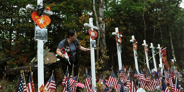 A woman views a memorial at the site where seven bikers riding with the Jarheads Motorcycle Club were killed in a collision last month Saturday. Thousands of motorcyclists converged at the crash site at the conclusion of the 90-mile Ride for the Fallen 7 to remember the riders who were killed. (Paul Hayes/Caledonian-Record via AP)
