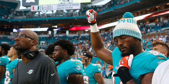 In this 2018 photo, then-Miami Dolphins defensive end Robert Quinn (94) raising his right fist during the anthem before a game against the Tampa Bay Buccaneers, in Miami Gardens, Fla. (AP Photo/Wilfredo Lee, File)