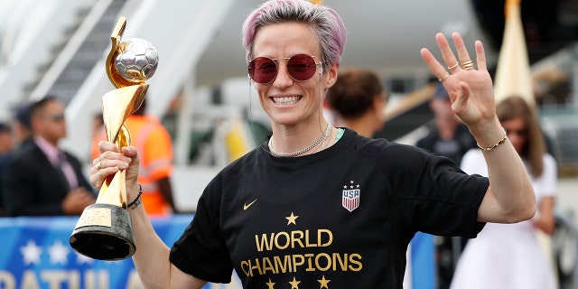 United States women's soccer team member Megan Rapinoe holds the Women's World Cup trophy as she celebrates in front of the media after arriving at Newark Liberty International Airport, Monday, July 8, 2019, in Newark, N.J. (AP Photo/Kathy Willens)