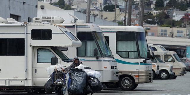 A person pushes a cart past parked RVs along a street in San Francisco on June 27, 2019. A federally mandated count of homeless in San Francisco increased 17 percent in two years, driven in part by a surge of people living in RVs and other vehicles.