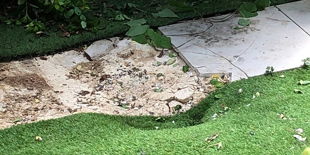 He landed partly on a small patio and partly on the grass, leaving cracked paving and a massive dent. (SWNS)